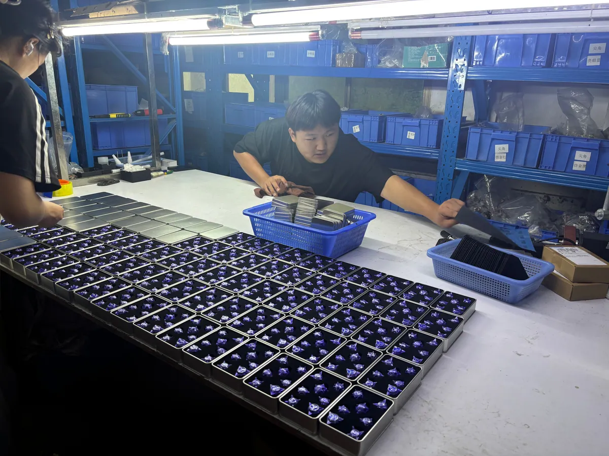 Workers packing finished custom dice into metal presentation boxes