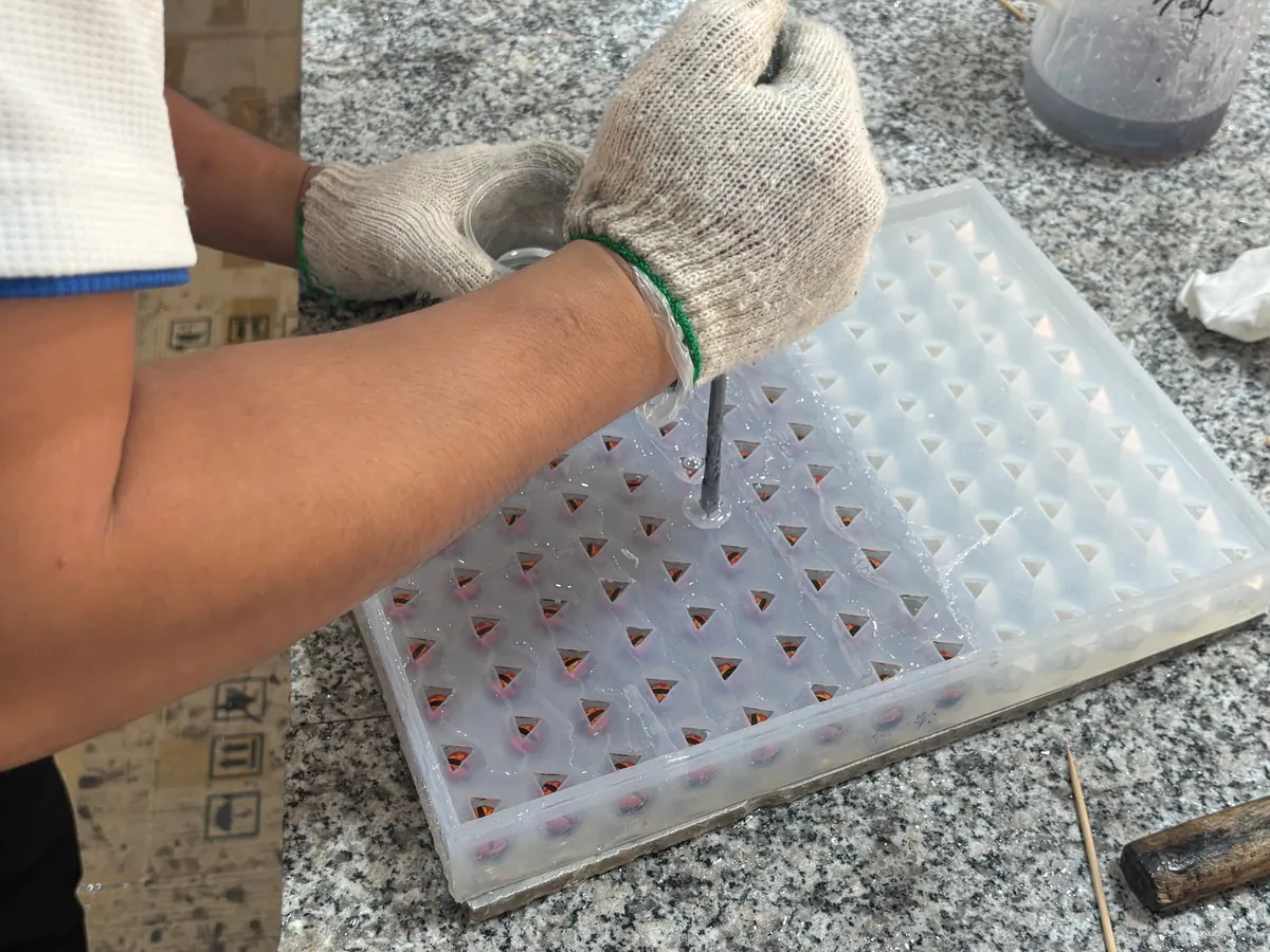 Worker casting resin into a multi-cavity custom dice mold
