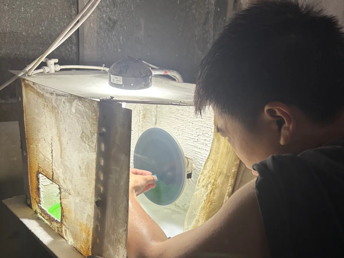 Worker polishing a resin die against a finishing wheel